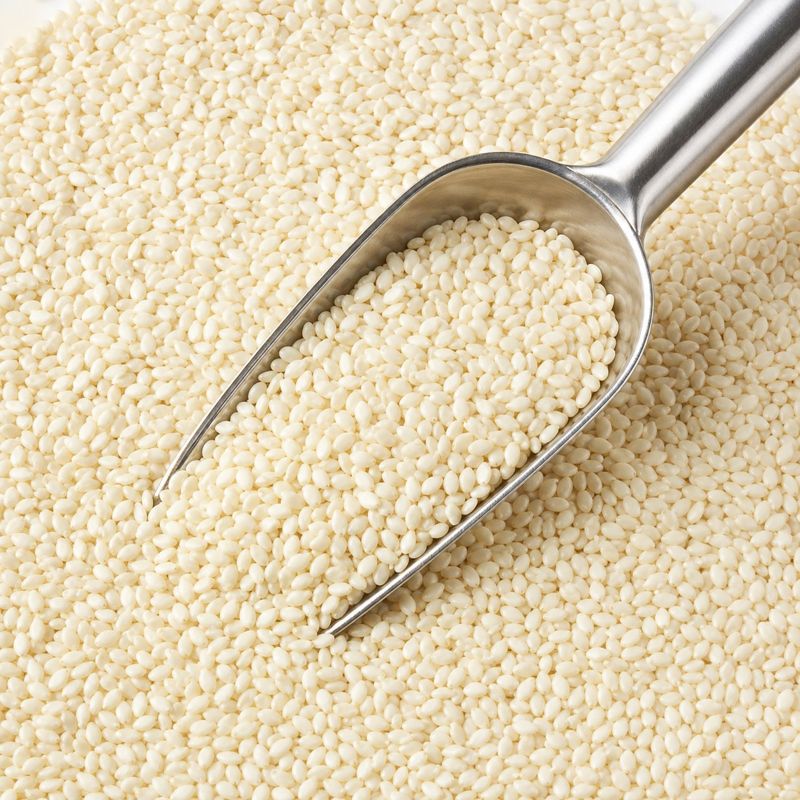 Perfectly uniform machine-sorted premium white sesame seeds with a stainless steel scoop